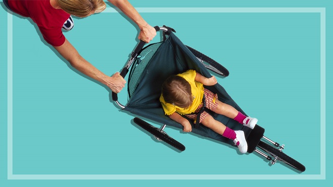 a child being pushed in a three-wheel pram on a teal background